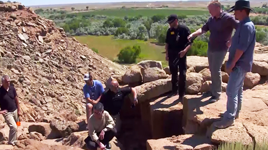 A group of men survey a rocky hillside