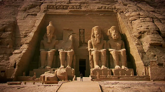 A large stone temple with four god-like figures in front