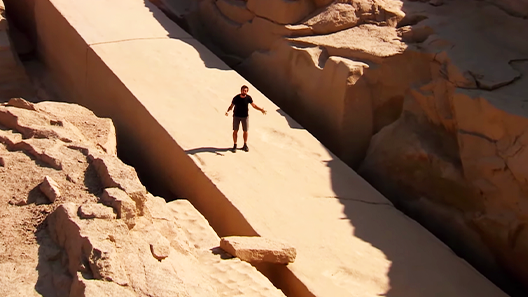 Derek Muller standing on a large stone slope