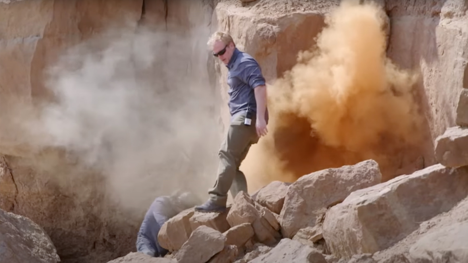 Travis Taylor turns his back on some orange smoke emitting from rocks