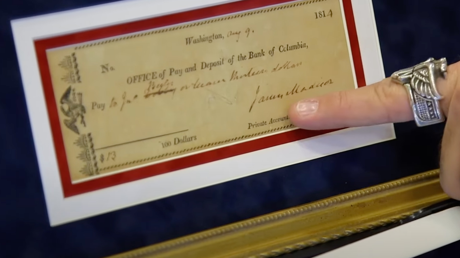 A man points at a framed cheque from the 19th century