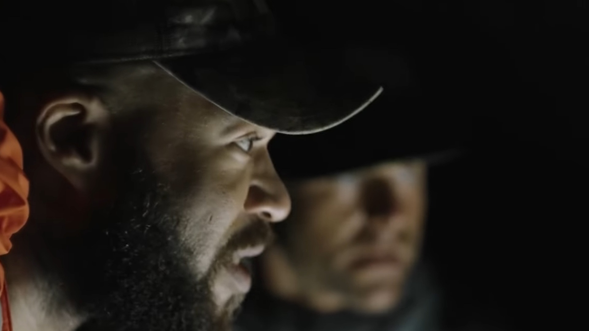 Kru Williams inside a cave - the side profile of his face is visible and lit up by torch light. To his side, out of focus, is Adam Palmer