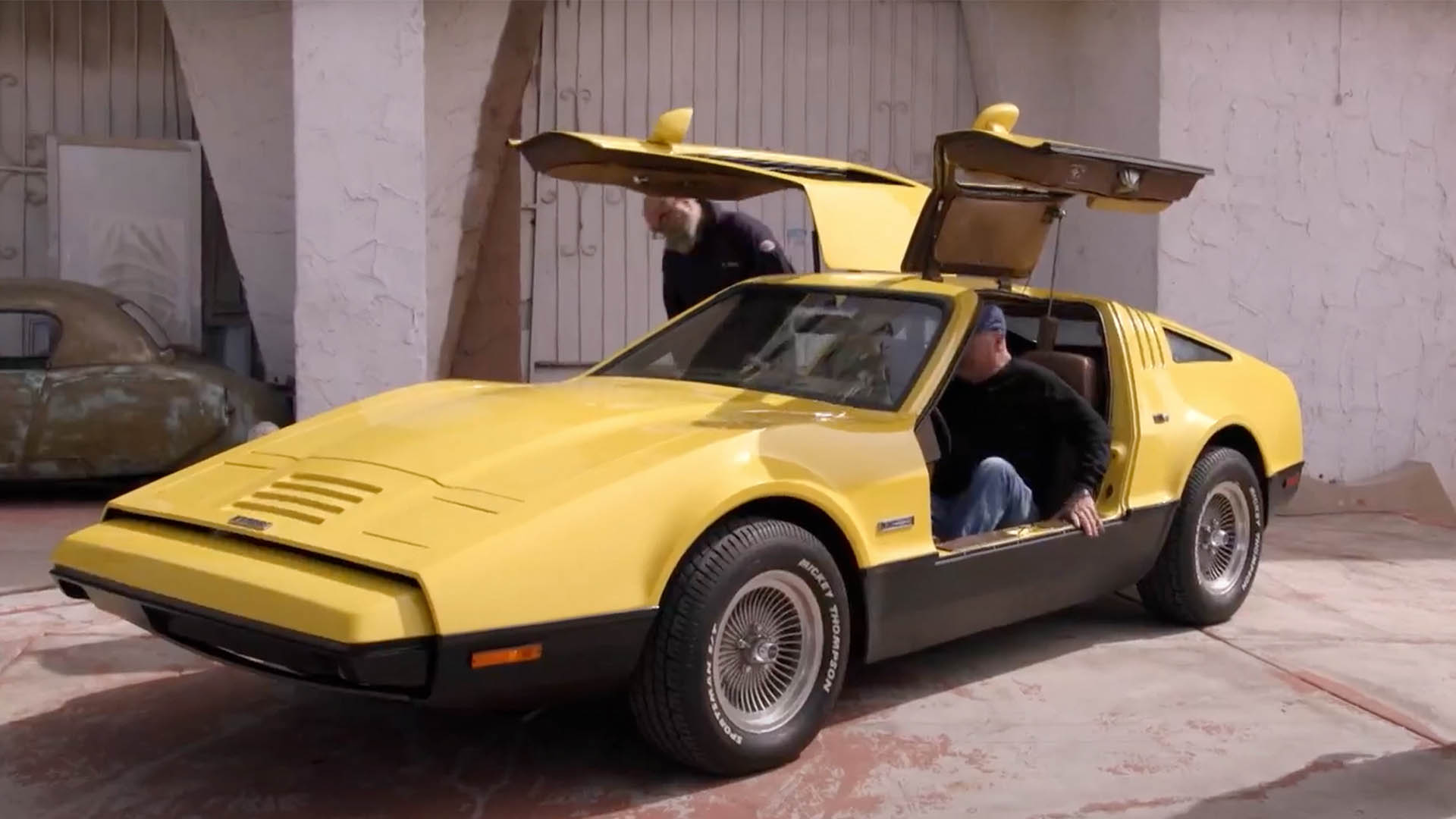 A yellow car from the 1970s with his winged doors open