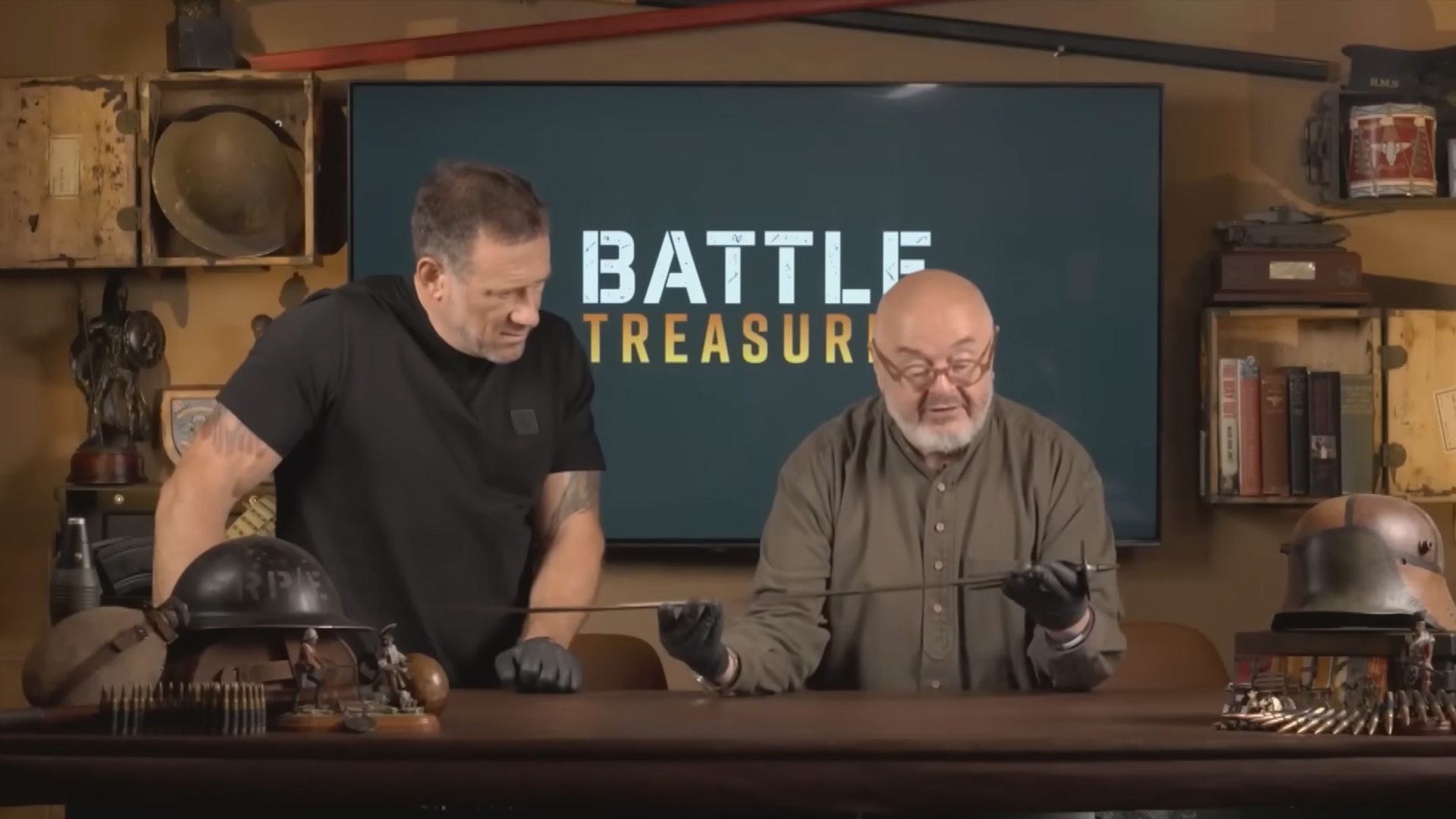 Bruce Crompton holds an old sword while Jason Fox also looks at it