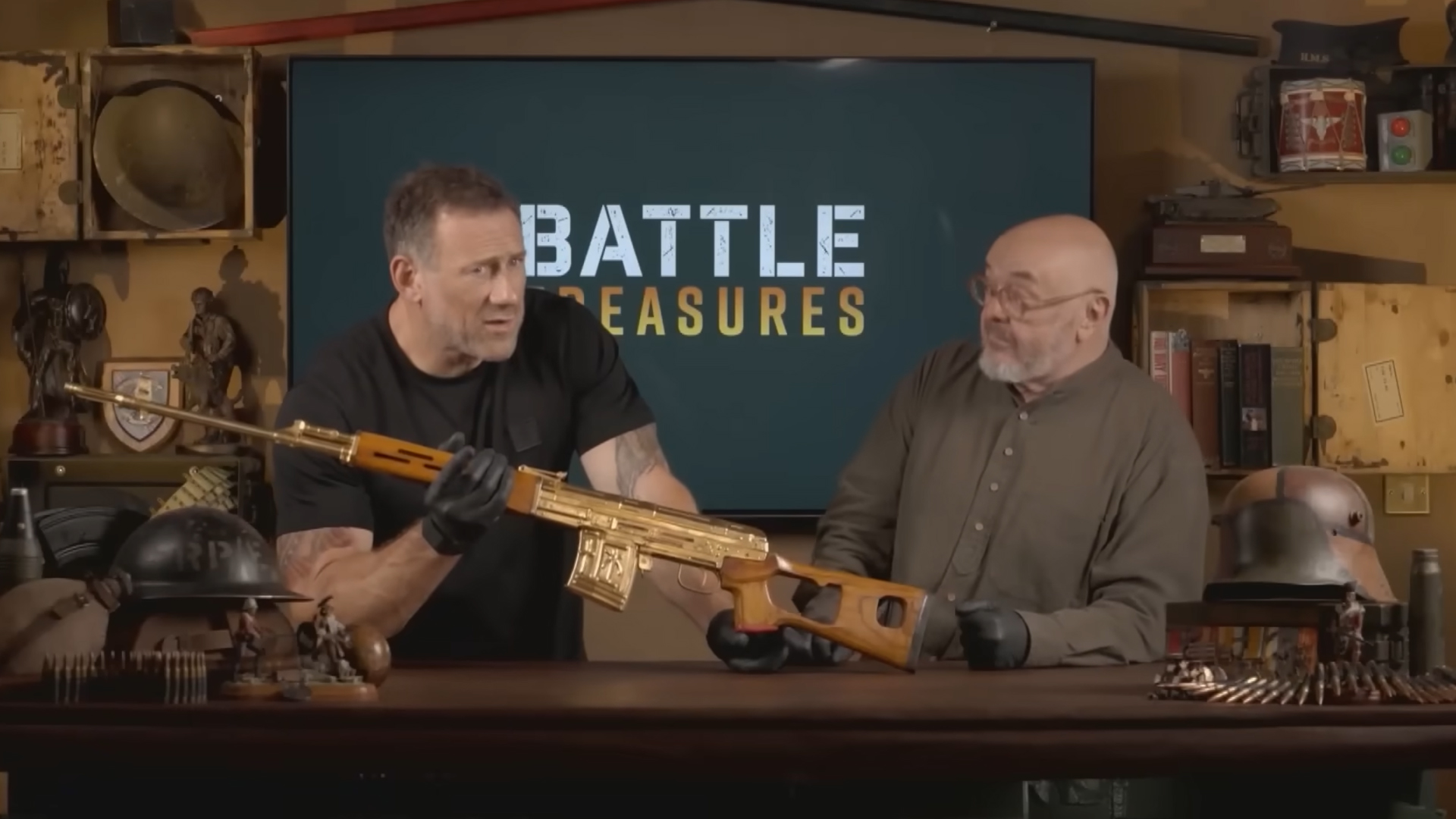 Jason Fox and Bruce Crompton inspecting a gold rifle on the set of 'Battle Treasures'