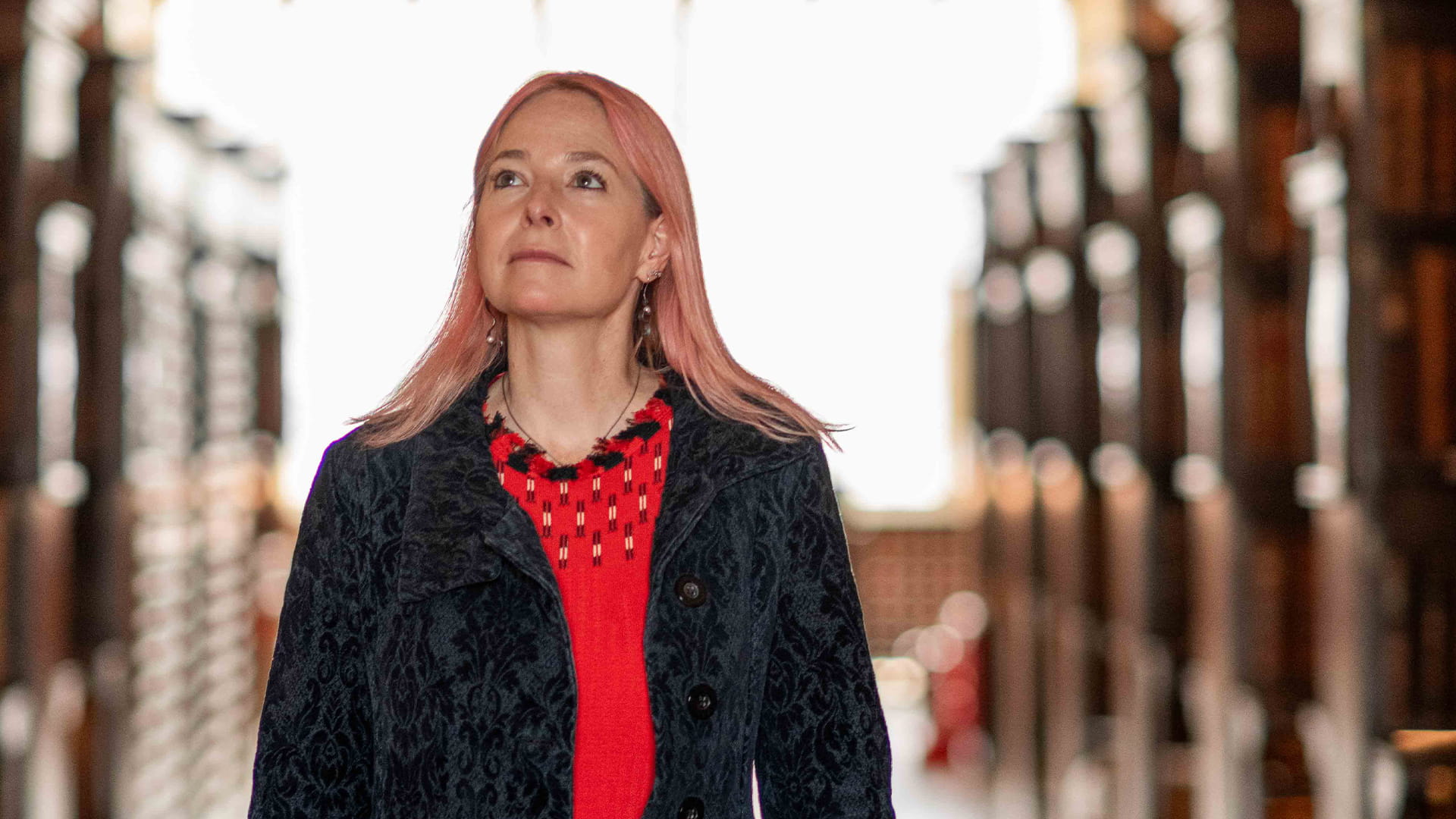 Professor Alice Roberts walking through library admiring the books