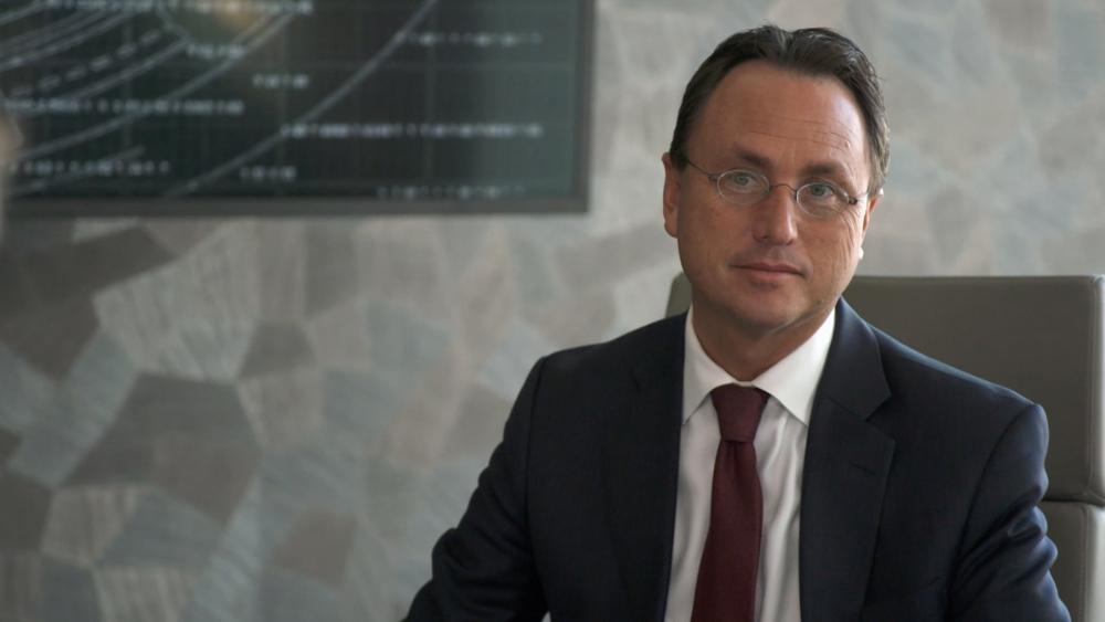 Brandon Fugal wearing a suit and tie while sitting in a boardroom