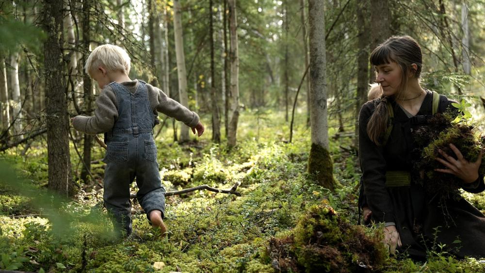 Soraya Painter collects moss as one of her children walks through the forest barefoot