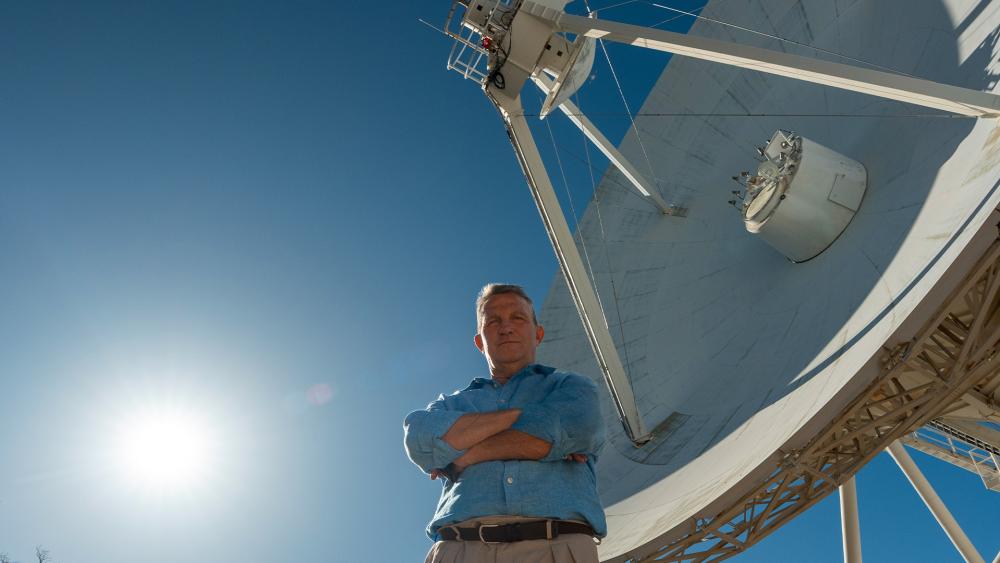 Bradley Walsh standing in front of a large radio telescope at an observatory