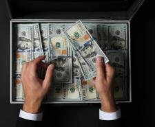 Businessman counting money over suitcase on dark background