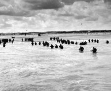 Black and white photograph of troops wading onto the Normandy beaches