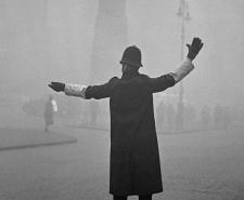 A London policeman directs traffic during a foggy day