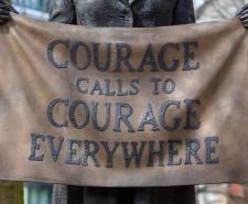 Statue of a suffragette holding a banner saying 'COURAGE CALLS TO COURAGE EVERYWHERE'