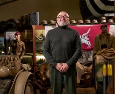 Bruce Crompton standing in front of a lot of military artefacts