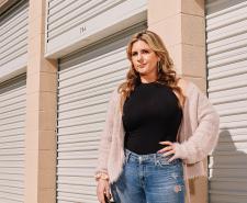Brandi Passante stands with a hand on her hip in front of some storage lockers
