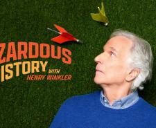 Henry Winkler looks up nervously as giant lawn darts land around him beside the title 'Hazardous History'