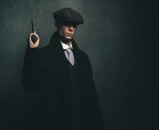 Dangerous retro 1920s English gangster standing with gun