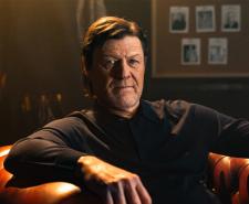 Sean Bean sitting in a large leather armchair