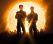 Rick and Marty Lagina hold shovels while standing in front of a glowing golden coin