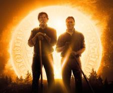 Rick and Marty Lagina hold shovels while standing in front of a glowing golden coin