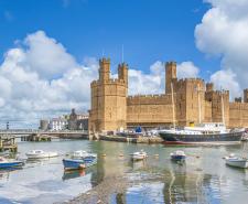 Caernarfon Castle with boats moored on the River Seiont in the foreground