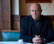 Ross Kemp sitting in a cafe with a small coffee cup 