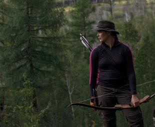 Carleigh Fairchild holding a bow and arrow in the forest