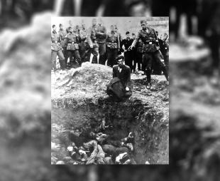 A Nazi solider points a gun at a Jewish man's head as he kneels over a mass grave