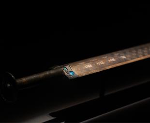 The Sword of Goujian on display in a museum against a black backdrop