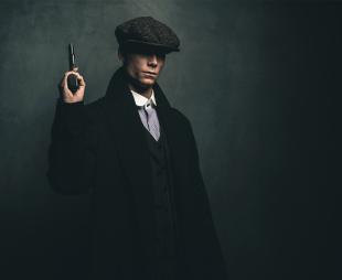 Dangerous retro 1920s English gangster standing with gun