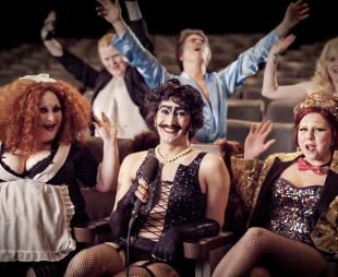 Documentary contributors sitting in theatre seating dressed up as members of the Rocky Horror cast
