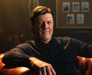 Sean Bean sitting in a large leather armchair
