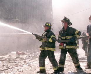 Firefighters spray a hose in the aftermath of the 9/11 attacks