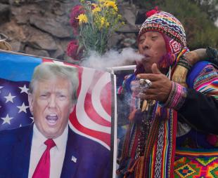 A Preuvian shaman blows smoke on an image of Donald Trump
