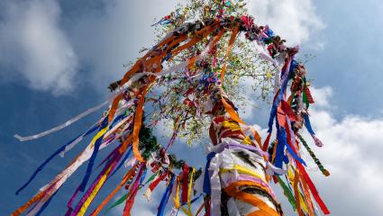 A colourful Maypole in front of a blue sky