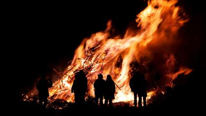 People stand in front of a large bonfire 
