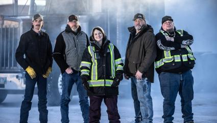 The Ice Road Truckers cast standing in front of a large truck in icy conditions