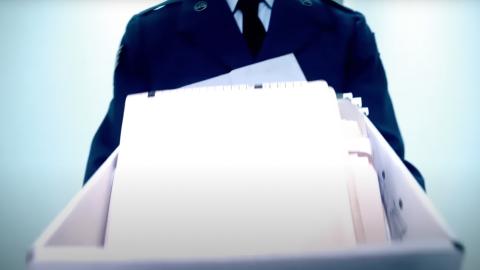 Government official walking down a corridor carrying box of documents