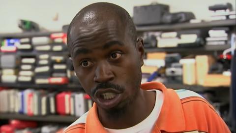 Male customer in Detroit's pawn shot arguing with an employee. The customer is wearing an orange polo shirt.