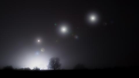 Glowing mysterious lights floating in the sky on a spooky foggy winters night