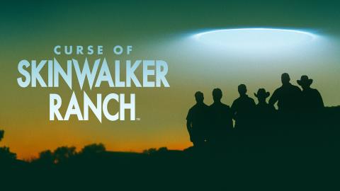 'CURSE OF SKINWALKER RANCH' - silhouettes of the Curse of Skinwalker cast standing against a green-orange sky with a mysterious flying saucer-shaped light above them