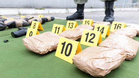 Police officers standing over packages of seized drugs