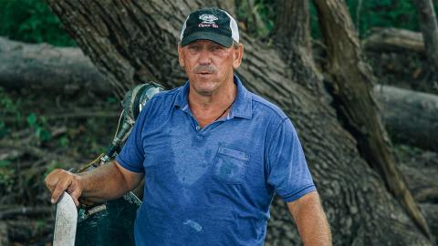 Troy Landry wearing a blue polo shirt while standing on a boat in the middle of the swamp