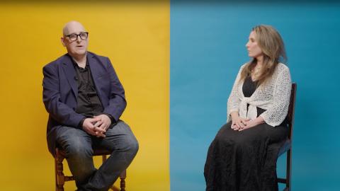 A man and a woman sitting either side of a divided background which is yellow on the left and blue on the right