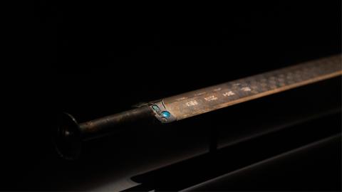 The Sword of Goujian on display in a museum against a black backdrop