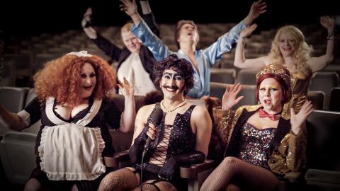 Documentary contributors sitting in theatre seating dressed up as members of the Rocky Horror cast