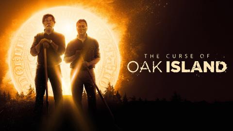 Rick and Marty Lagina hold shovels while standing in front of a glowing golden coin