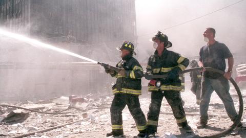 Firefighters spray a hose in the aftermath of the 9/11 attacks