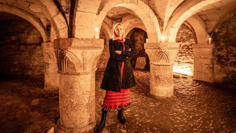 Alice Roberts standing with her arms folded in a church basement