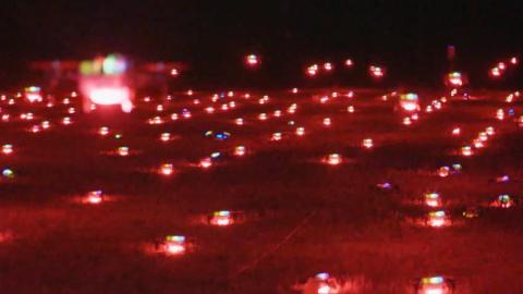 Hundreds of drones with red lights flying at night